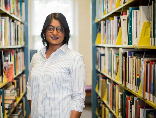 student in library between shelves of books